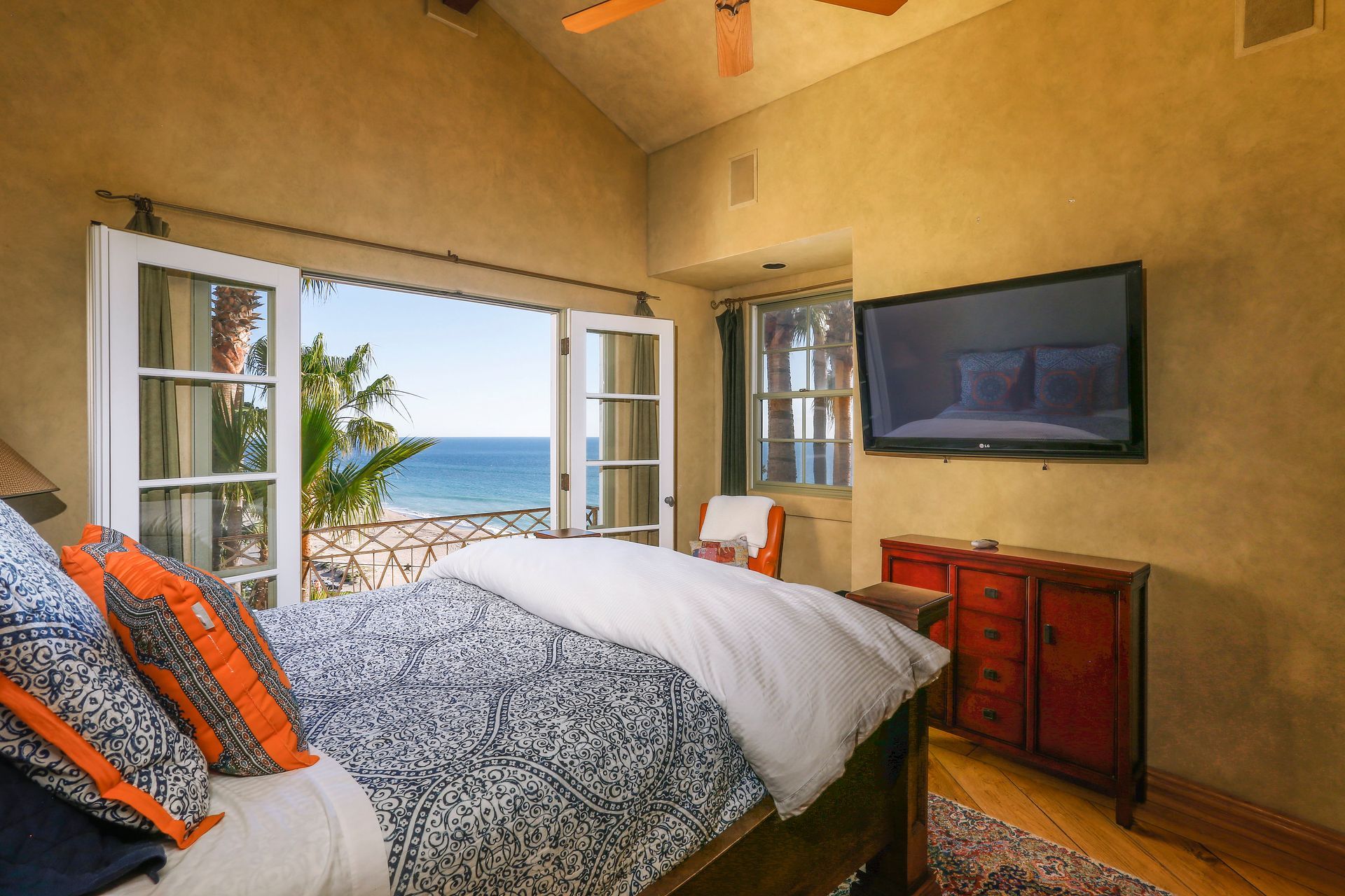 Bedroom with open windows overlooking the ocean, king bed, and wall-mounted TV