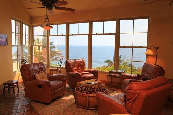 Cozy leather chairs in a sunlit room overlooking the ocean at sunset