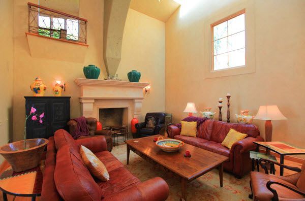 Cozy living room with red leather chairs, wooden coffee table, fireplace, and warm beige walls
