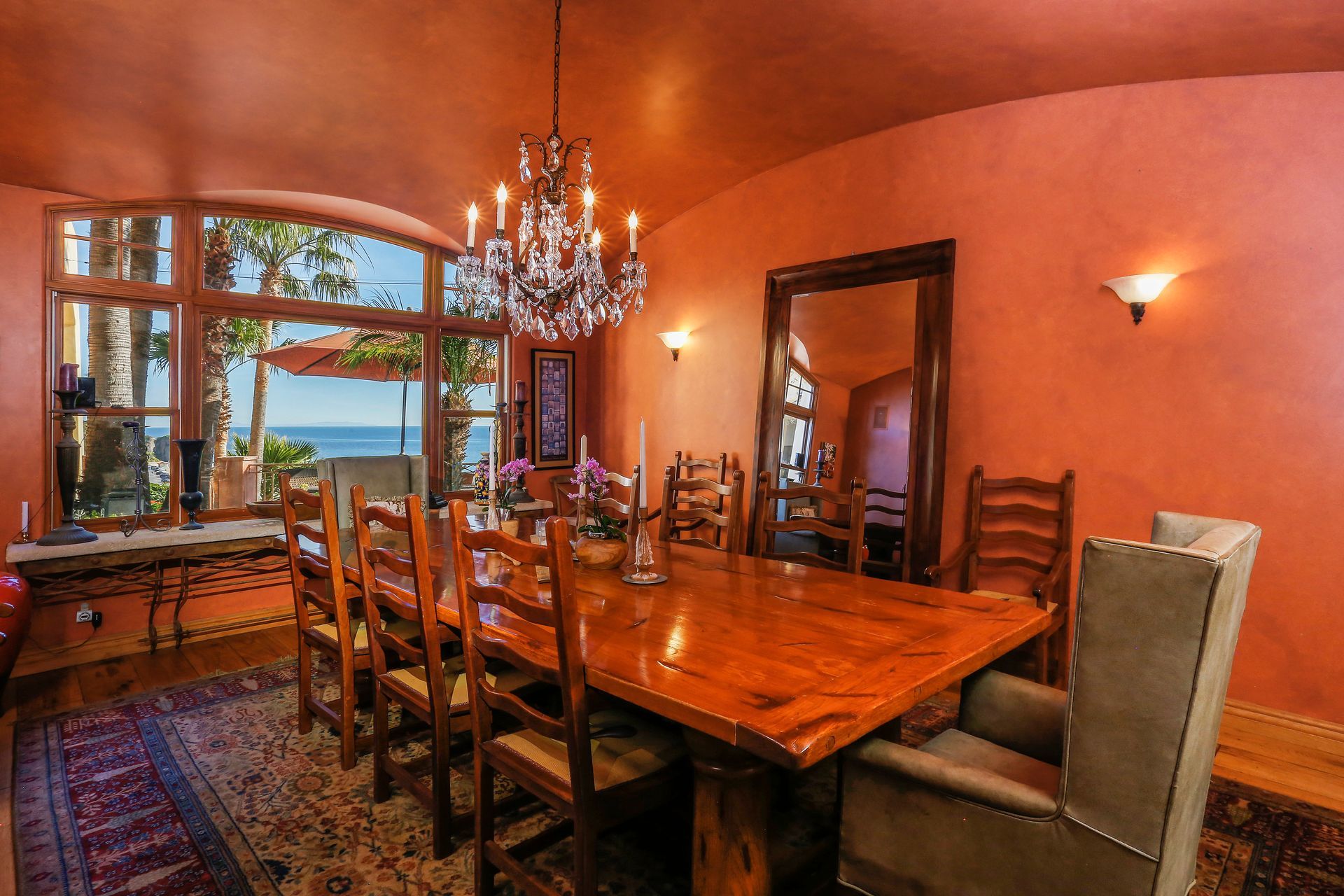 Elegant dining room with wooden table, chandelier, and large window overlooking the water