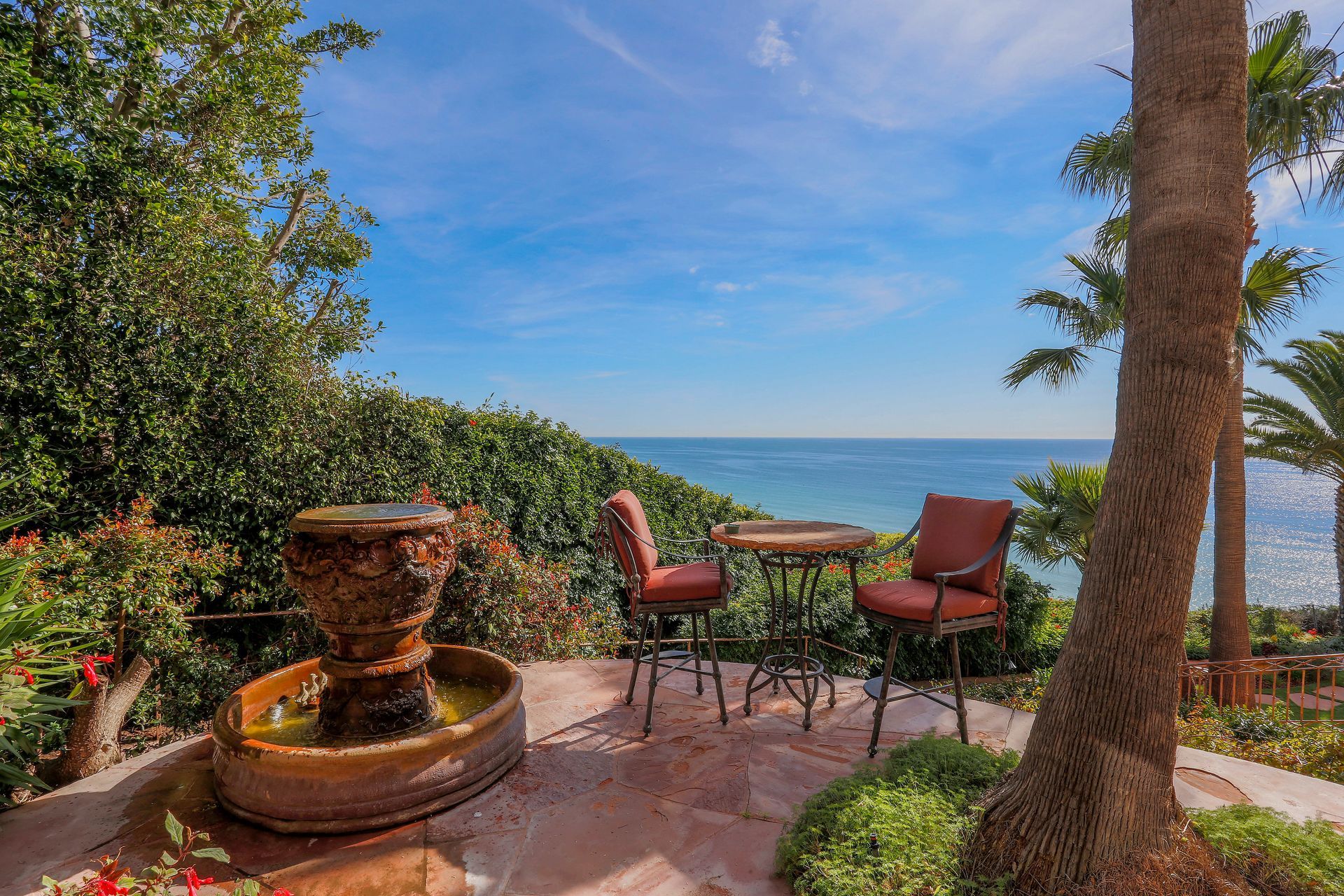 Patio with fountain and red chairs overlooking the ocean under a blue sky