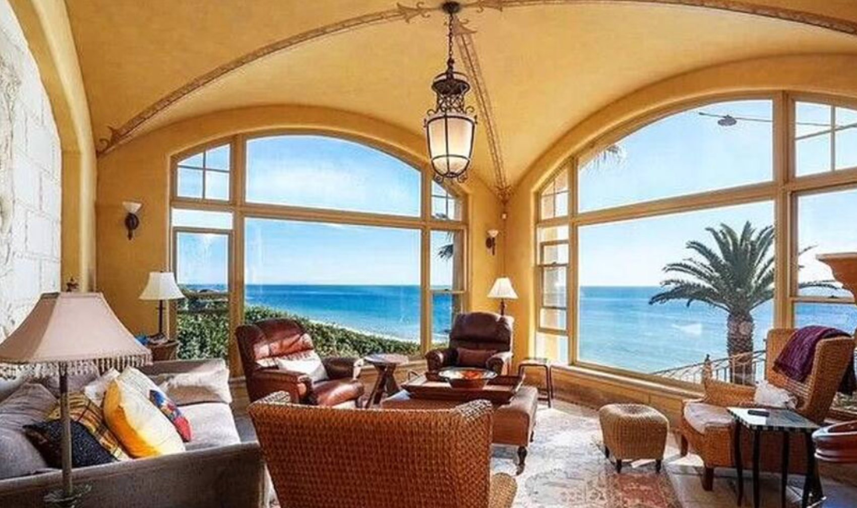 Luxury seaside living room with arched windows, warm decor, and ocean view