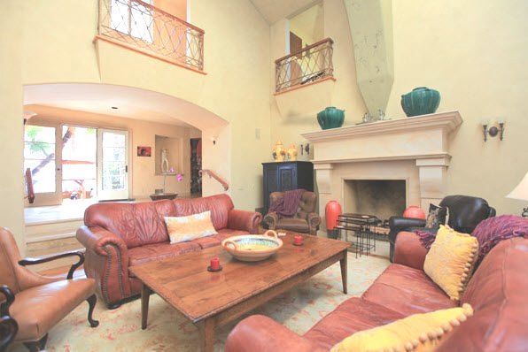 Warm living room with leather sofas, wooden coffee table, fireplace, and balcony railings above