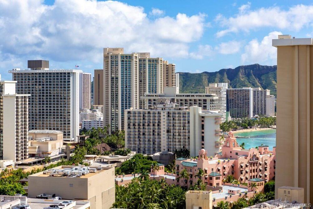 Coastal city skyline with high-rise hotels, turquoise bay, and mountains in the background