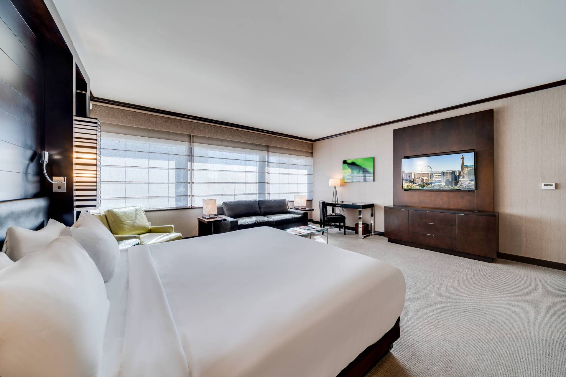 Modern hotel room with two beds, large windows, and a wall-mounted TV