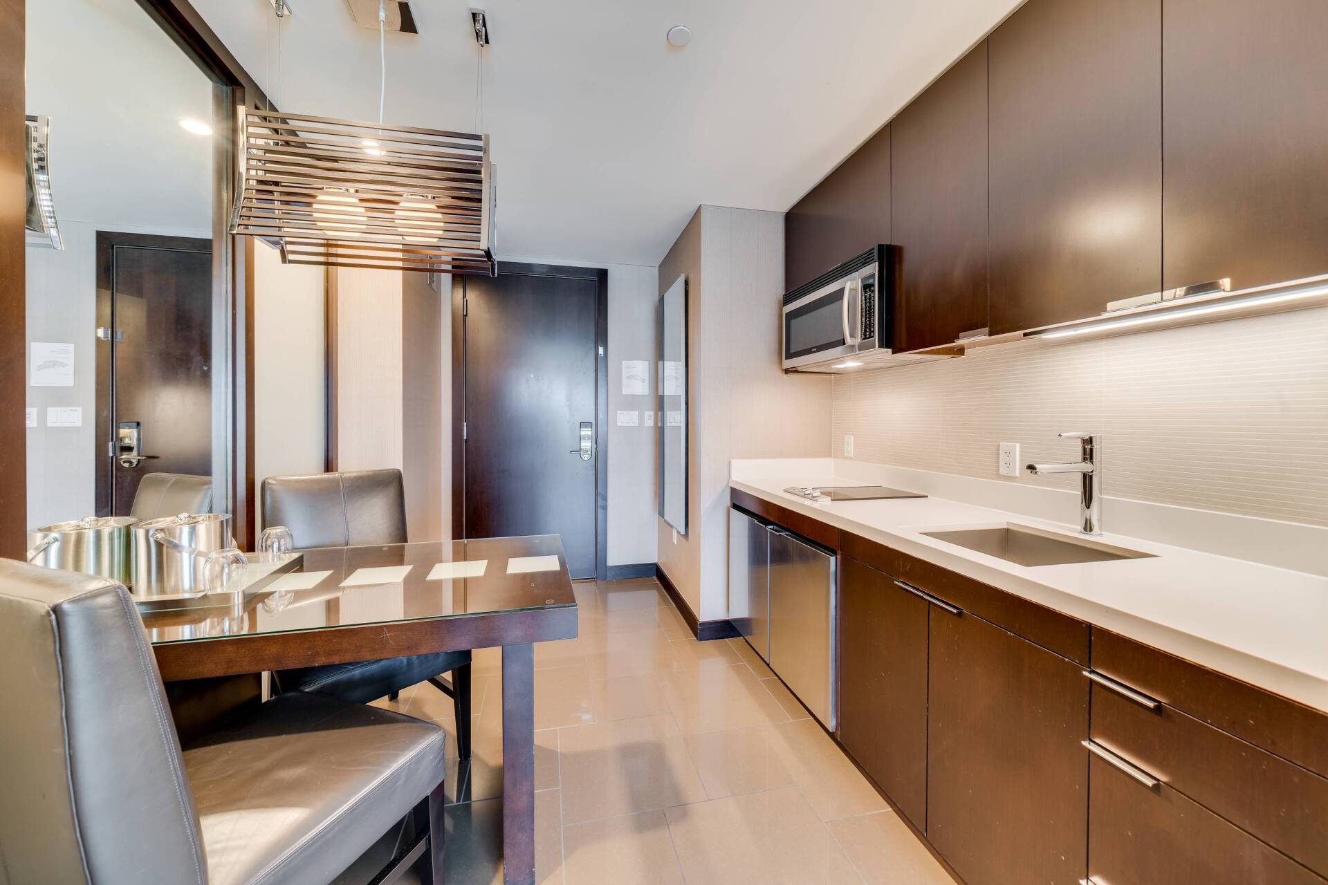 Modern kitchen and dining area with wood cabinets, stainless appliances, and a table set for four