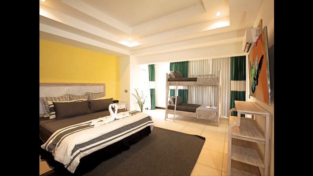 Bright modern bedroom with a bed, striped rug, wall art, and a sitting area by large windows