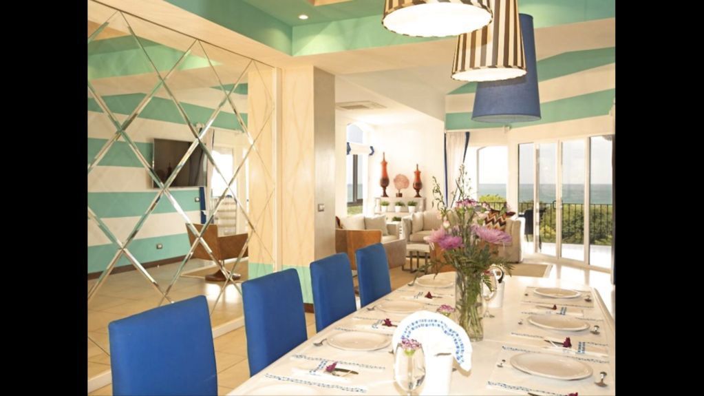 Elegant dining room with blue chairs, set table, flowers, and large windows overlooking water