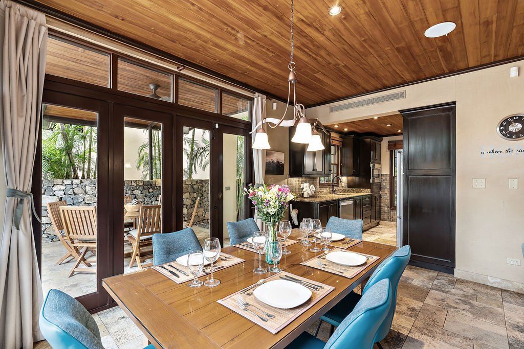 Dining room with wooden table, blue chairs, and large glass doors opening to a patio.