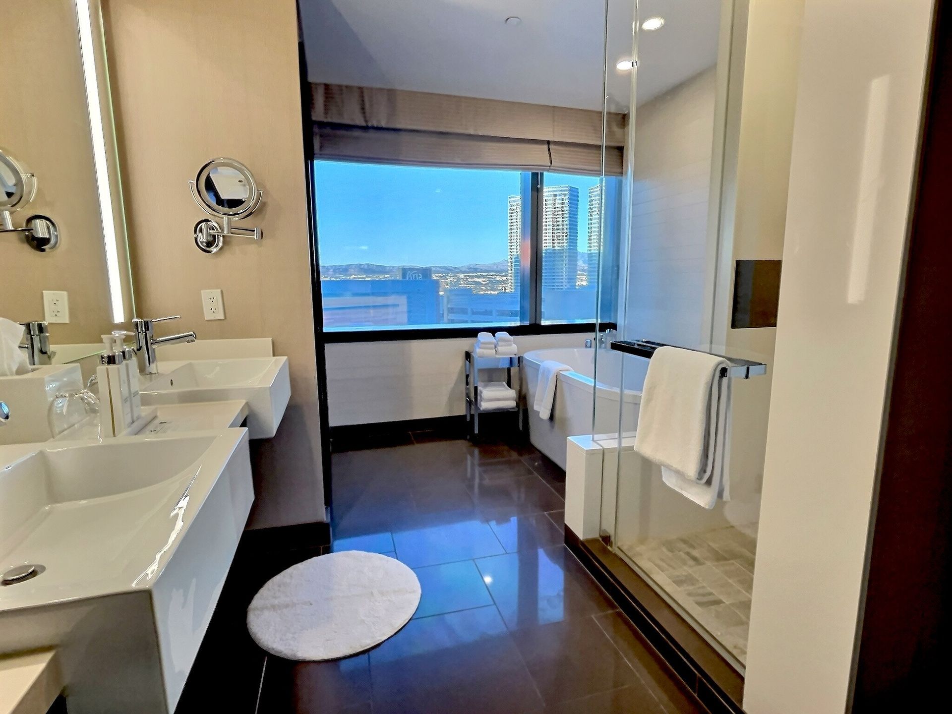Modern bathroom with twin sinks, large ocean-view window, and white towels