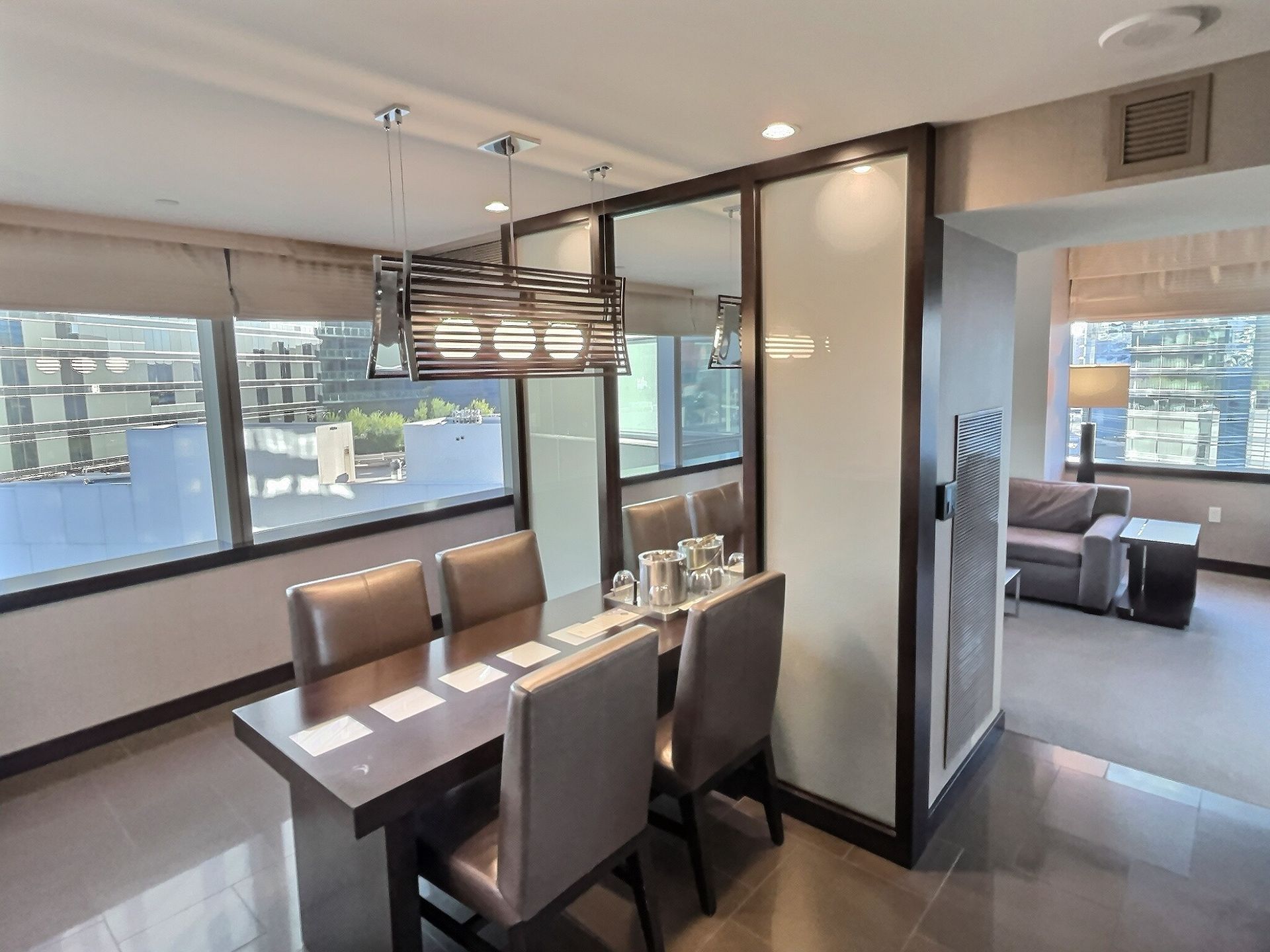 Modern dining area with glass partition, table and chairs, and city view through large windows