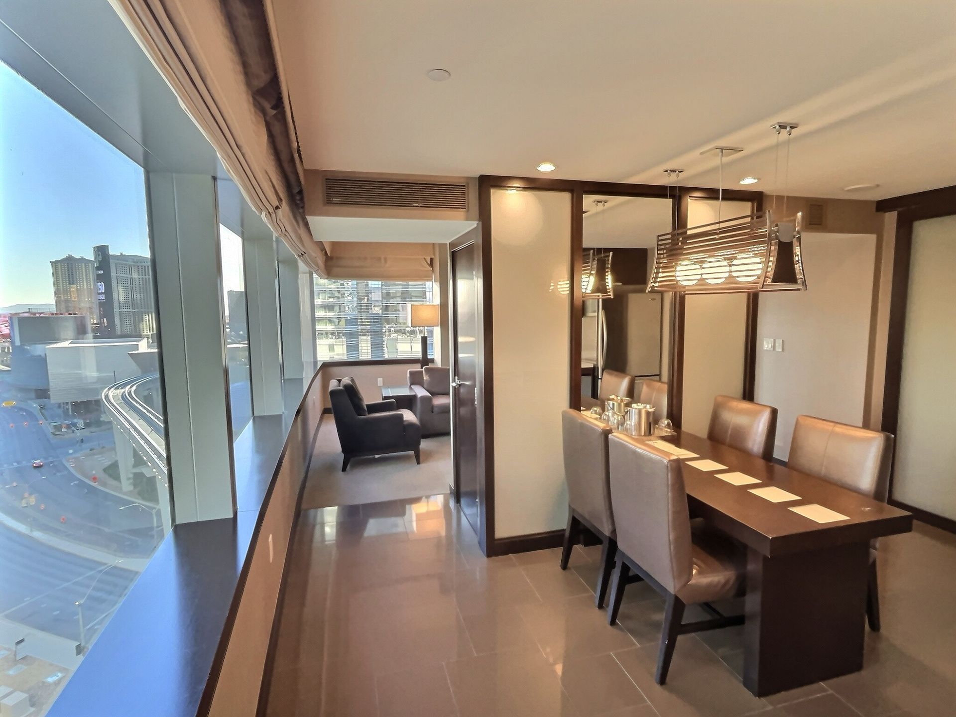 Modern dining room with a long table, chairs, and large windows overlooking a city view