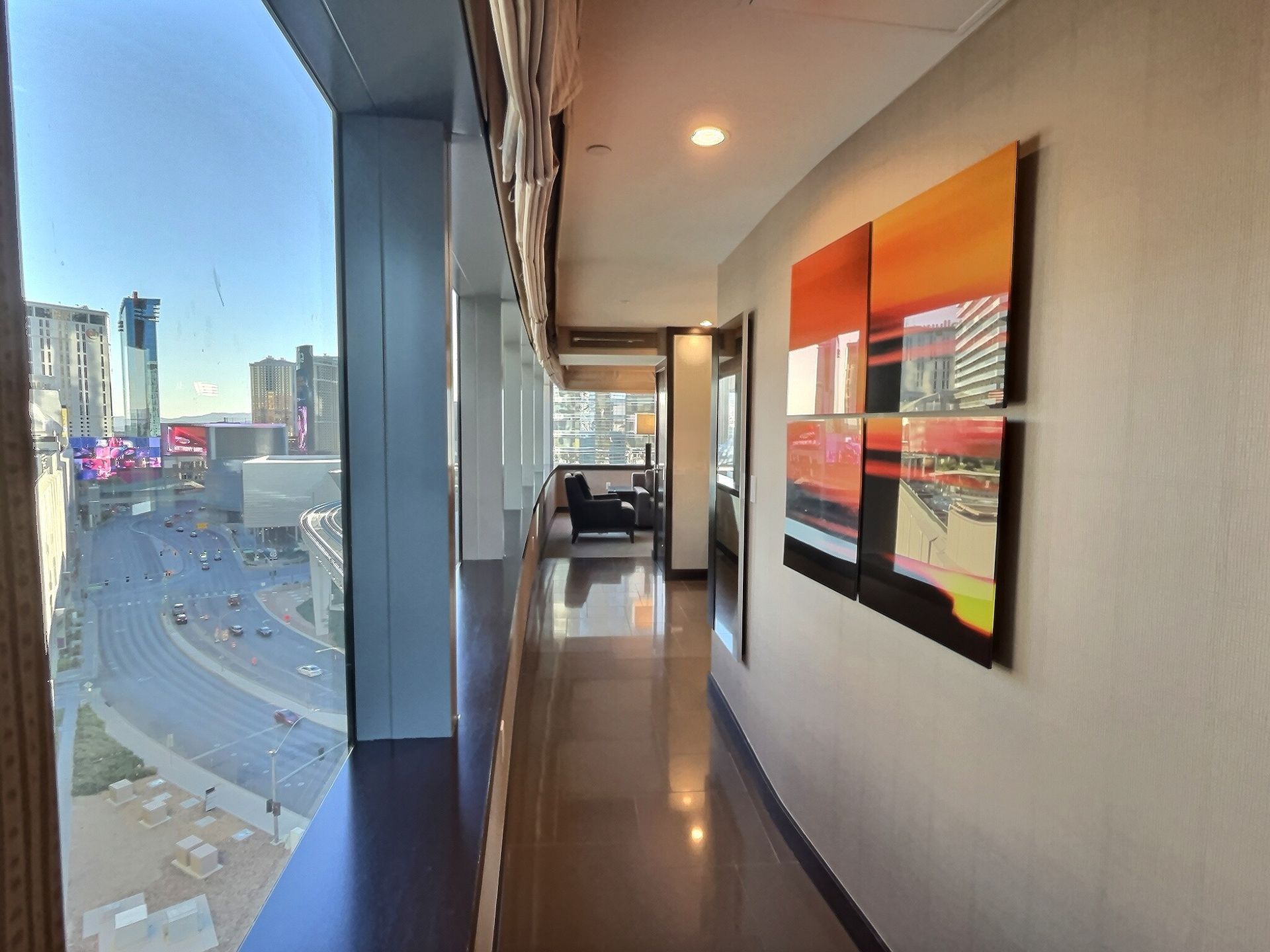 Modern hallway with city view through large windows and abstract wall art