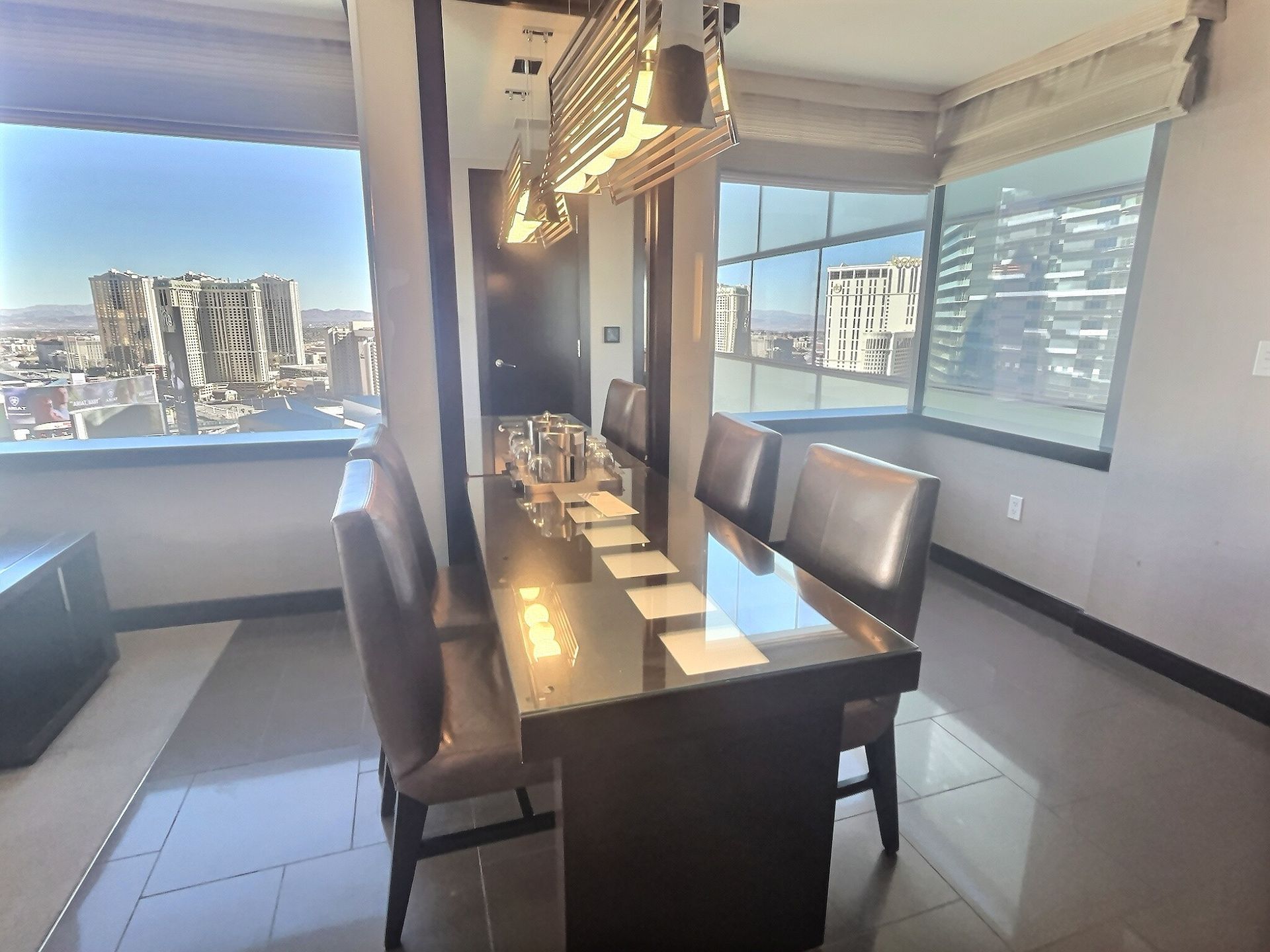 Modern dining room with a long black table, chairs, and large windows overlooking city and water views