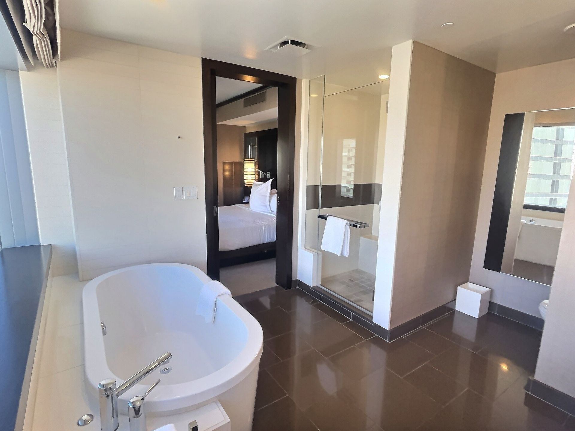 Modern bathroom with white tub, glass shower, vanity, and large mirror.