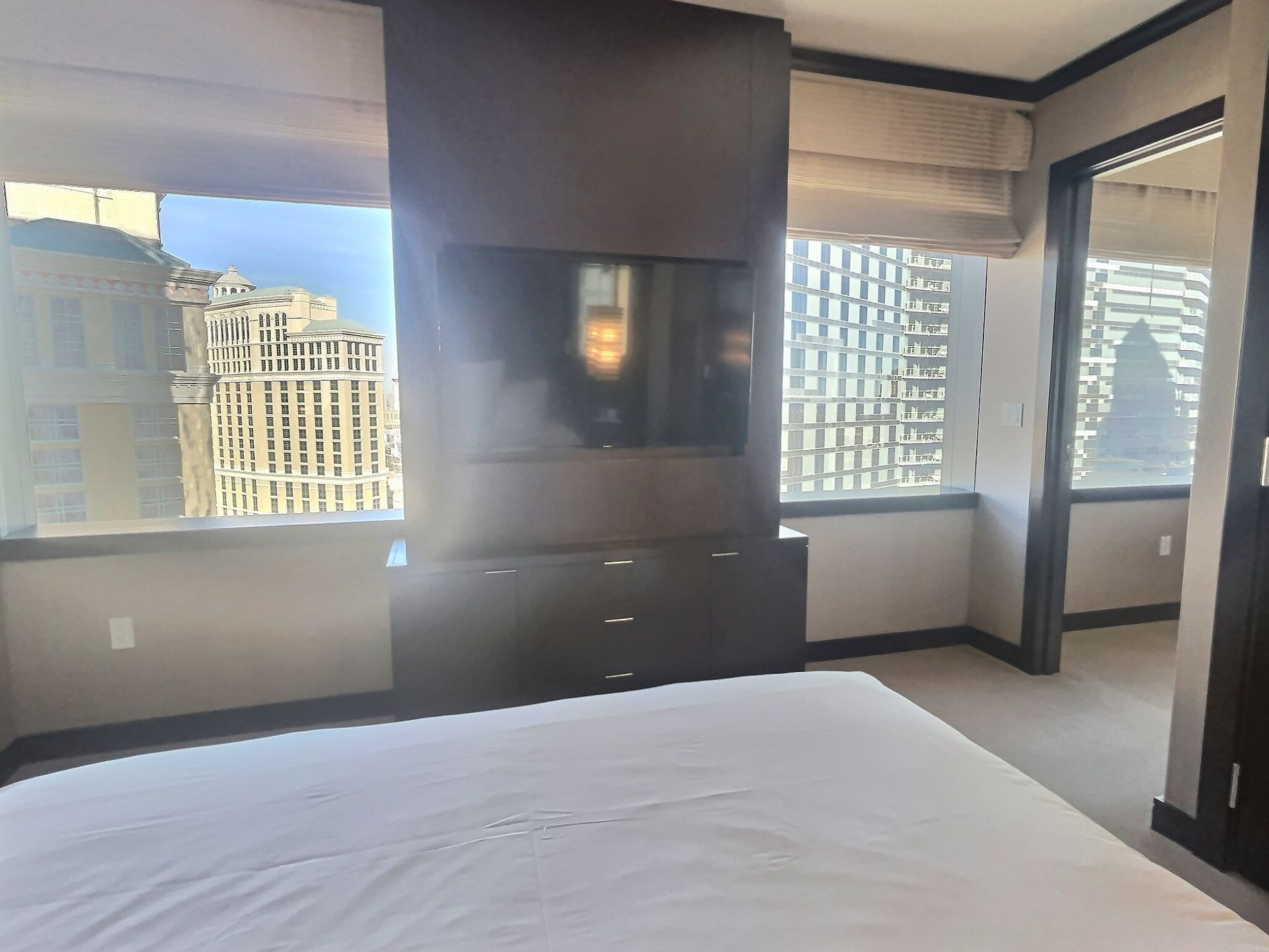 Modern hotel room with large windows, TV wall, and a neatly made bed