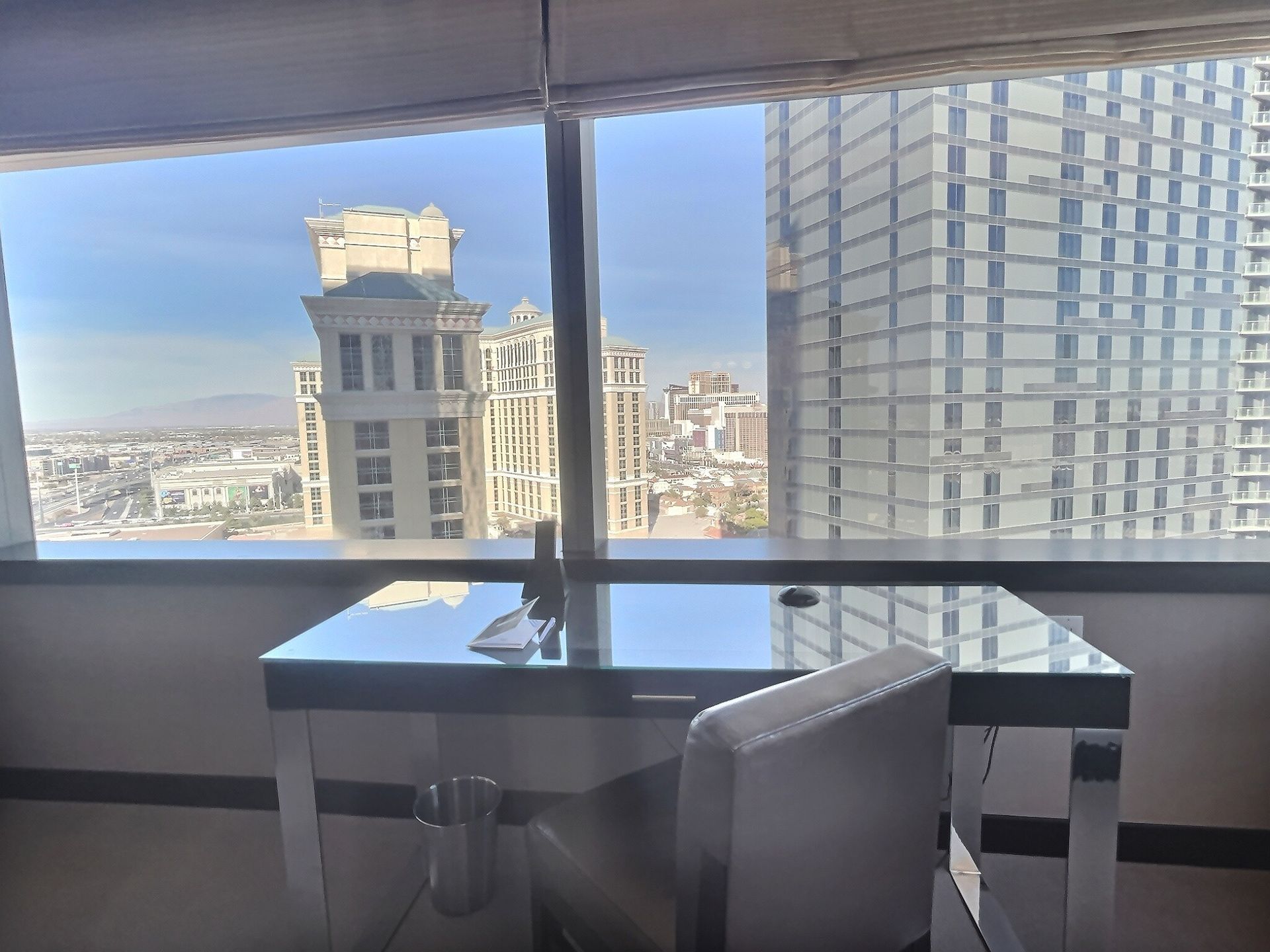 Modern office with glass desk and chair overlooking city skyline through large windows