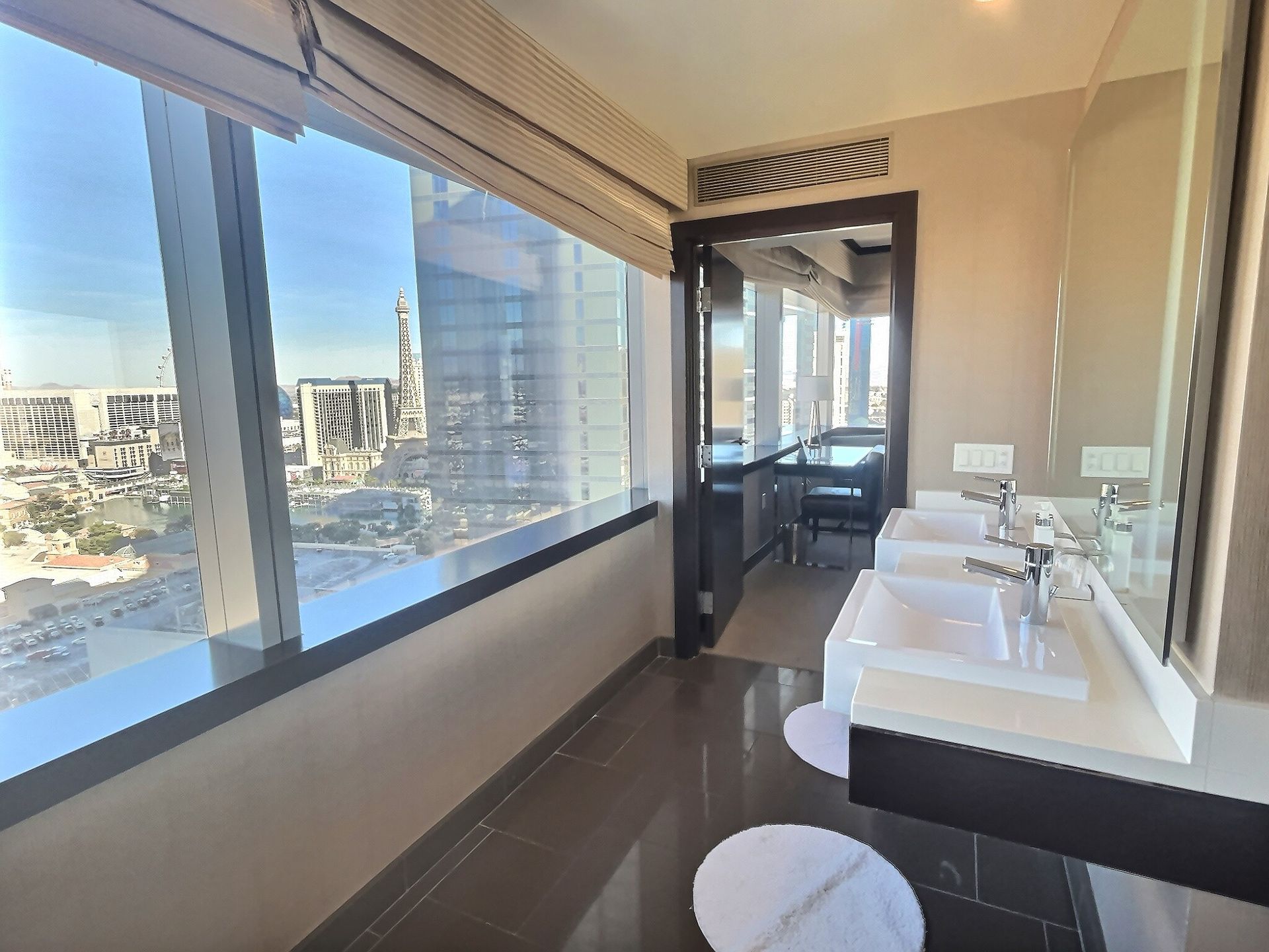 Modern bathroom with double sinks and large windows overlooking a city skyline