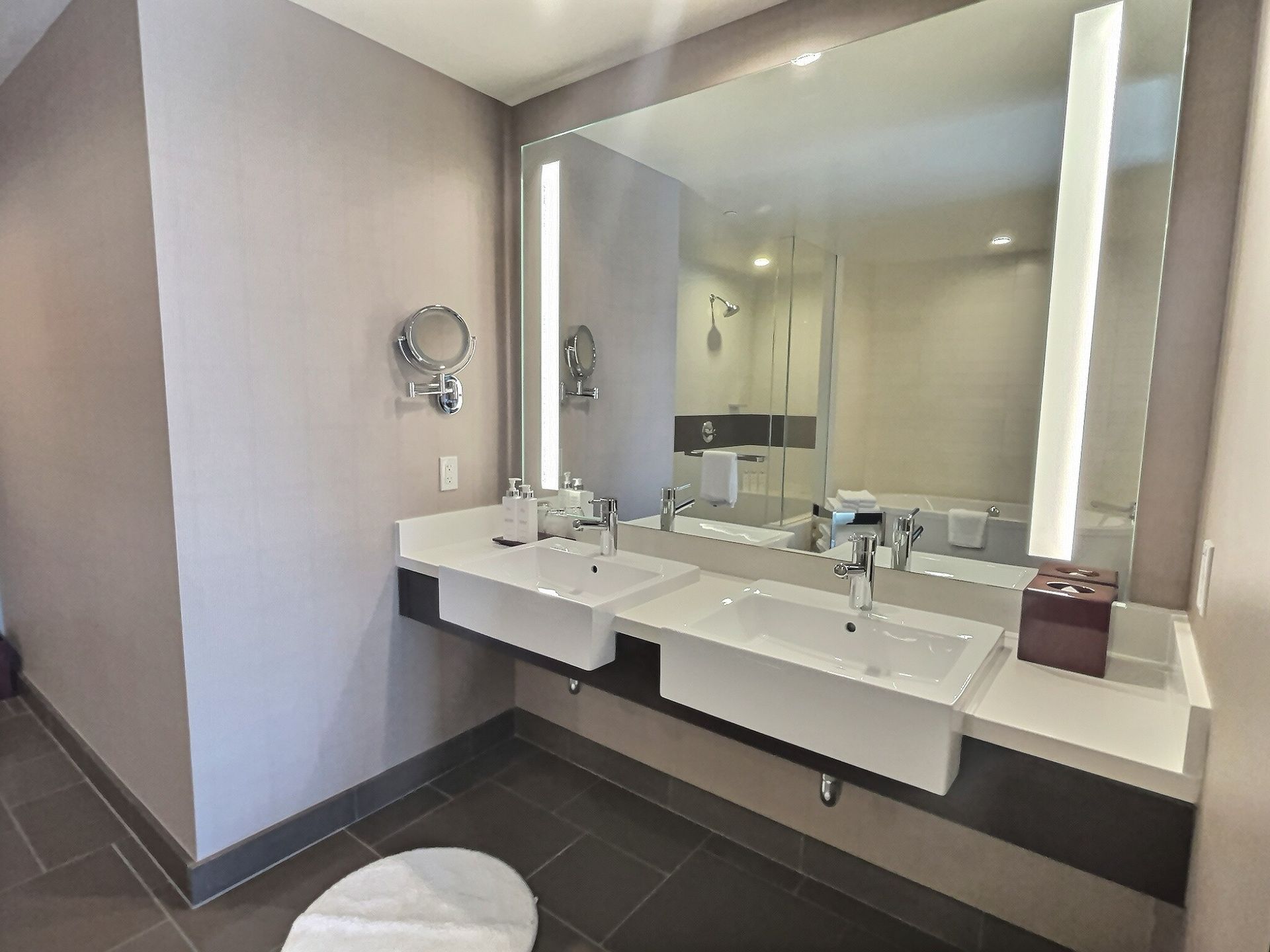 Modern bathroom with double sink, large mirror, and dark tile flooring