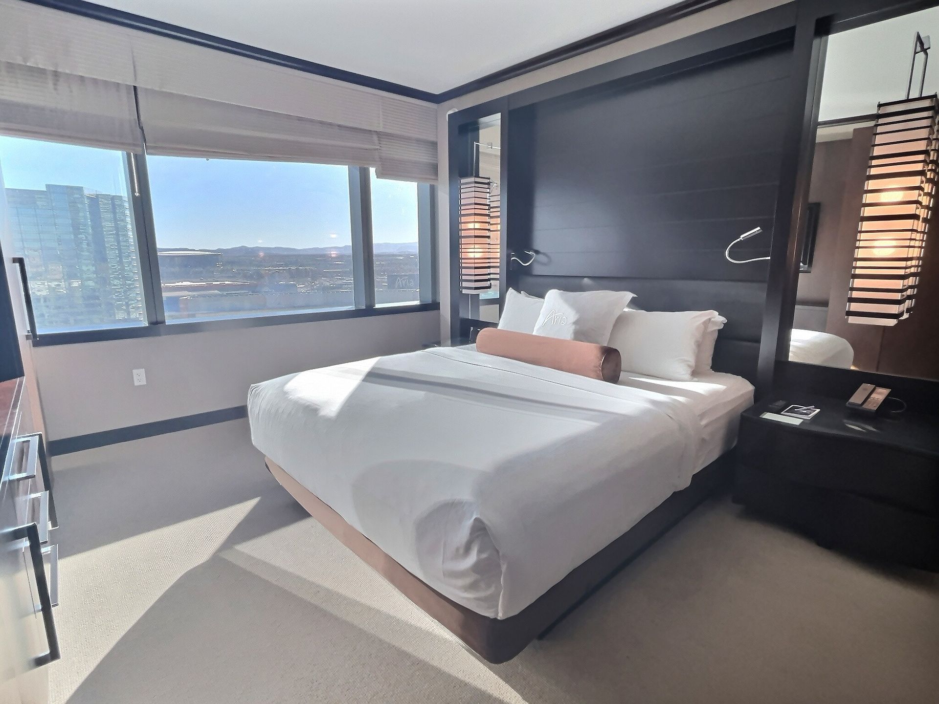 Modern bedroom with a large bed, floor-to-ceiling windows, and city views