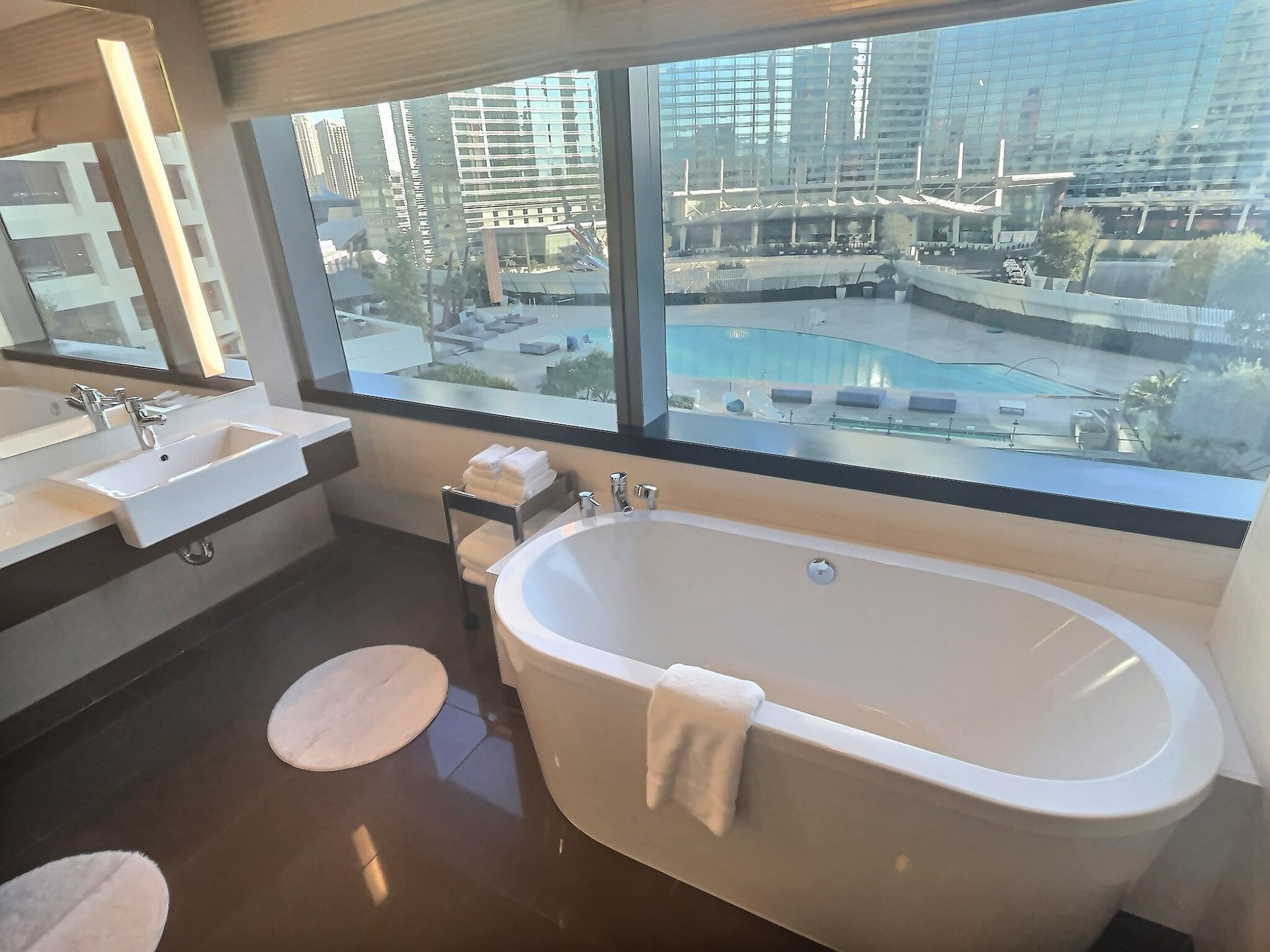 Modern bathroom with freestanding tub, large windows, and city view