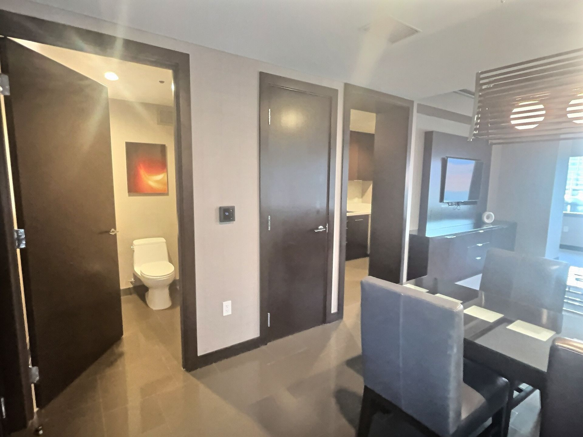 Modern apartment interior with dark doors, bathroom, and dining area by a window