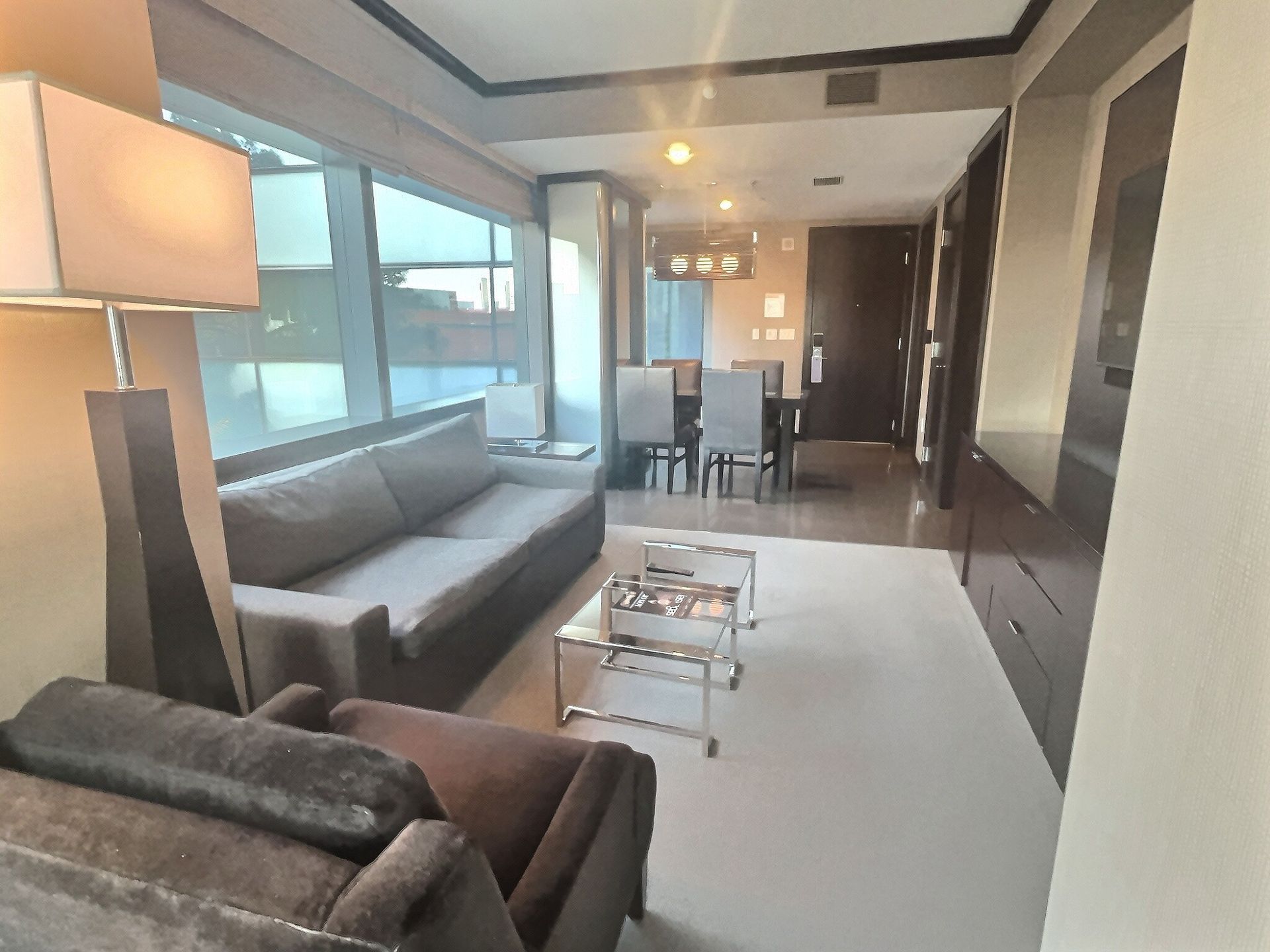 Modern living room with gray sectional sofa, coffee table, floor lamp, and dining area by large windows