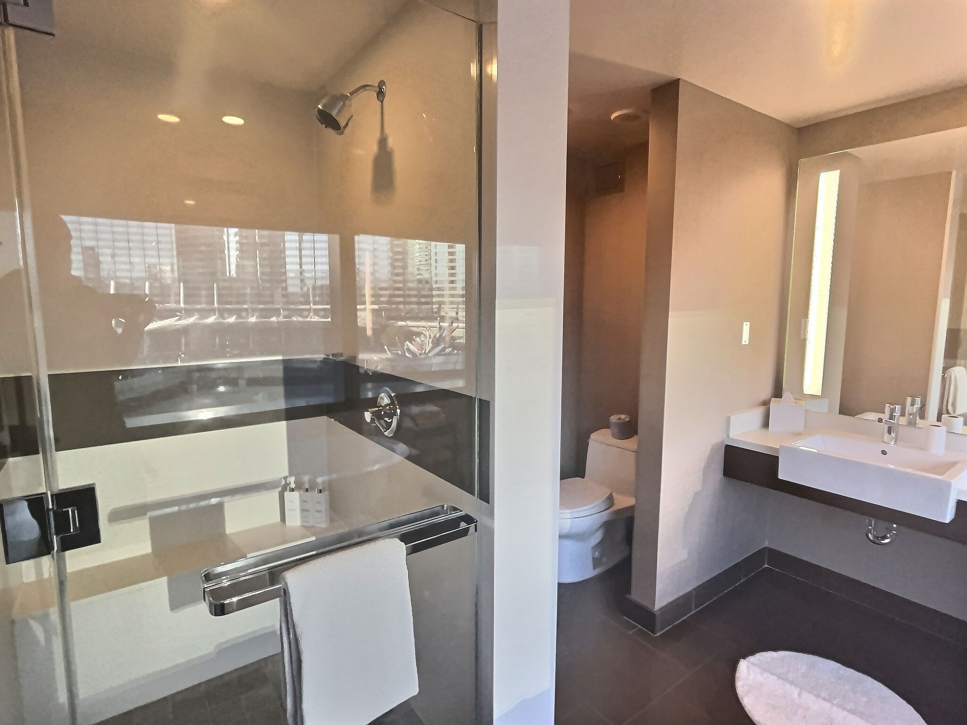 Modern bathroom with glass shower, white sink, and beige walls