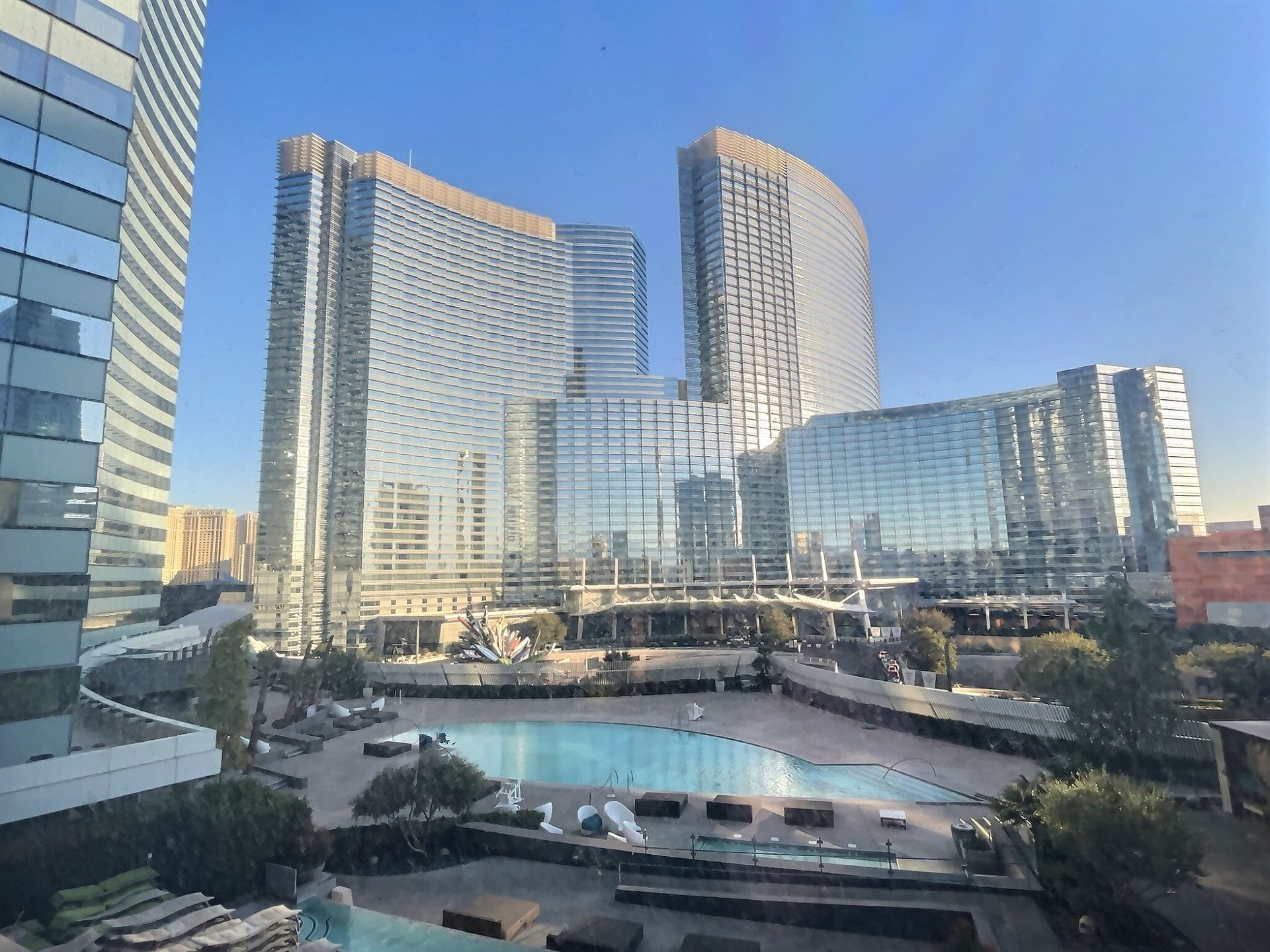 Modern glass high-rises beside a reflective courtyard pool under a clear blue sky