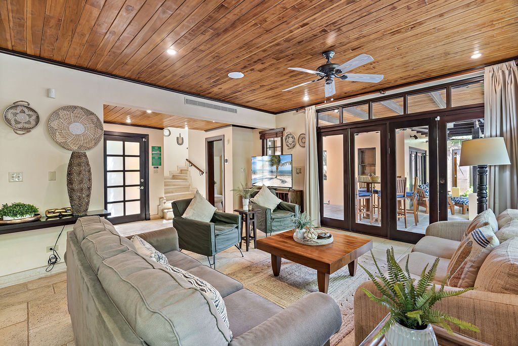 Bright living room with wood ceiling, large windows, beige sofas, and a coffee table
