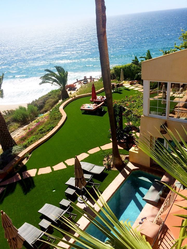 Oceanfront resort with green lawn, lounge chairs, pool, and beach view