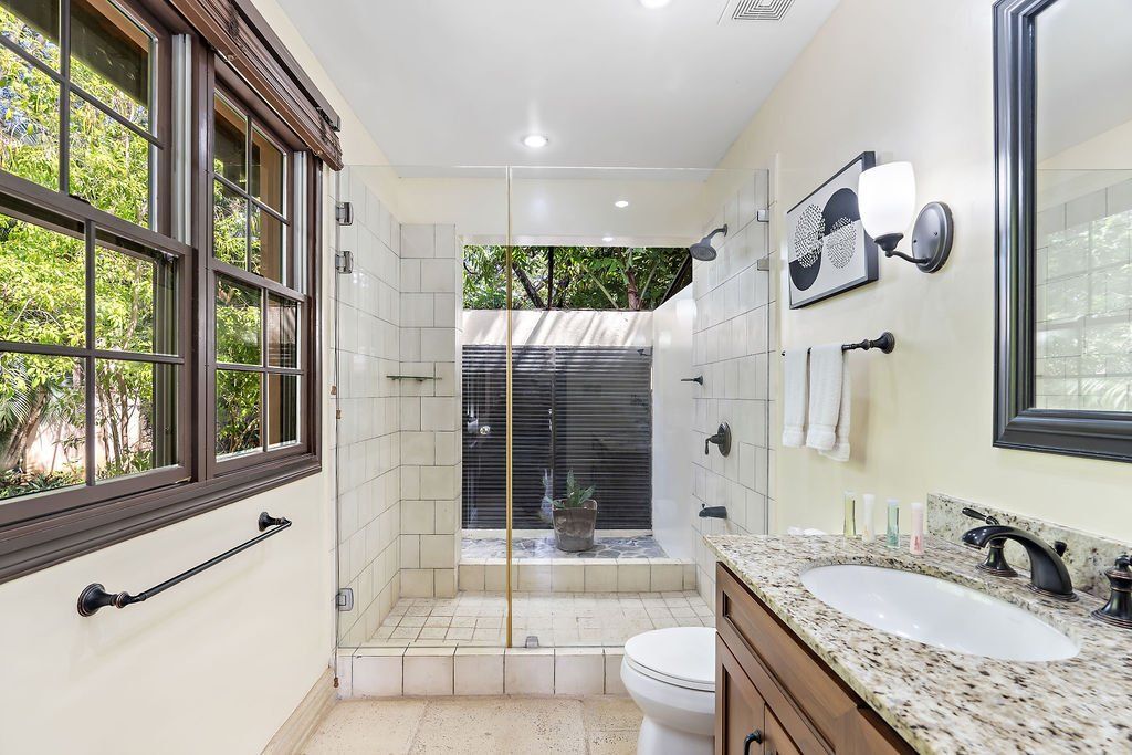 Bright bathroom with glass shower, granite vanity, large windows, and tiled floor