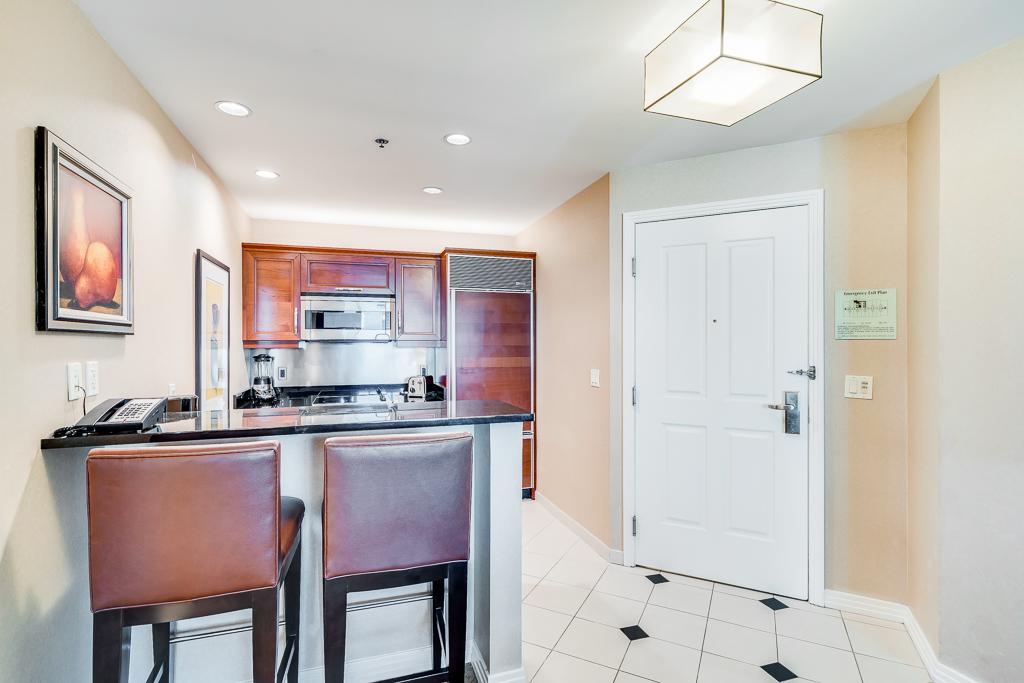 Bright kitchen and entryway with bar stools, stainless appliances, and white front door