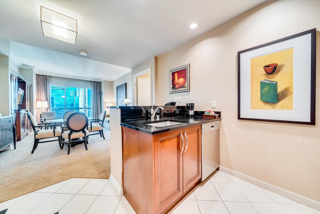 Bright open-concept living space with a wooden kitchen island, white tile floor, and wall art.