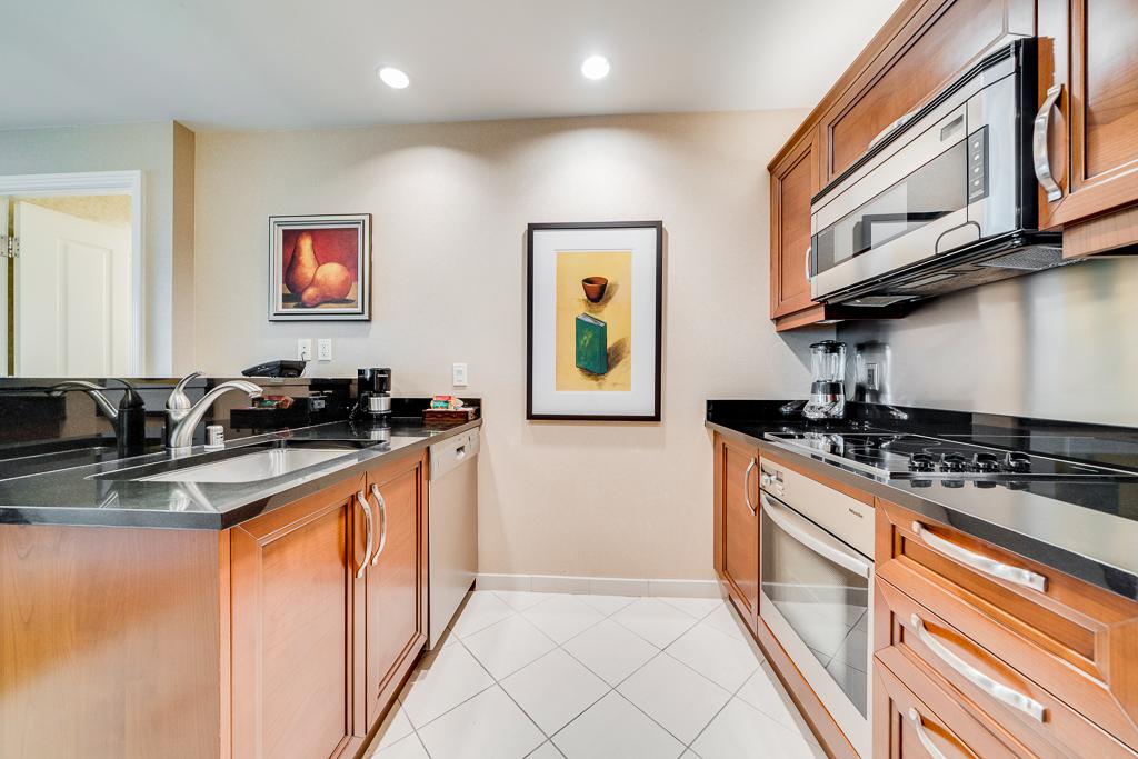 Modern kitchen with wood cabinets, black countertops, stainless appliances, and framed wall art
