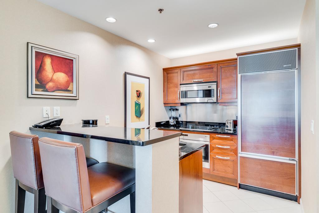 Modern kitchen with breakfast bar, stainless steel appliances, and two upholstered stools