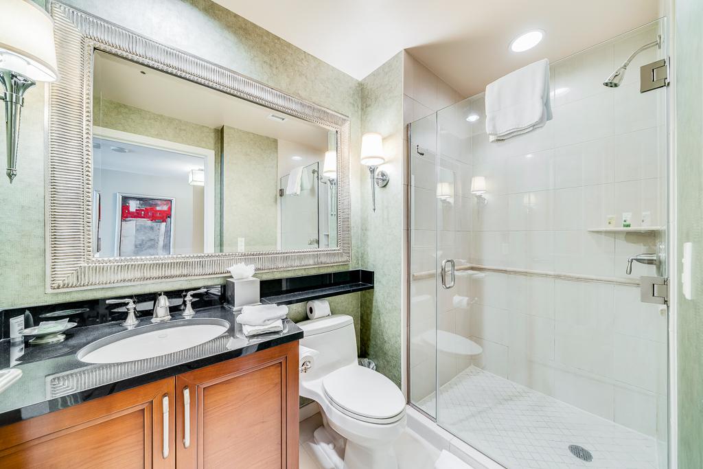 Modern bathroom with marble vanity, large mirror, and glass-enclosed shower