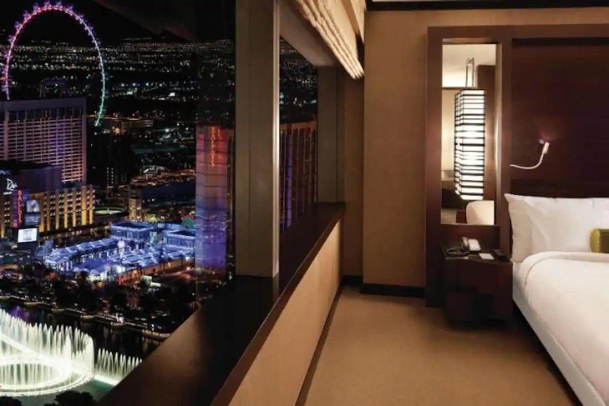 Hotel room with large city view at night, lit Ferris wheel outside the window