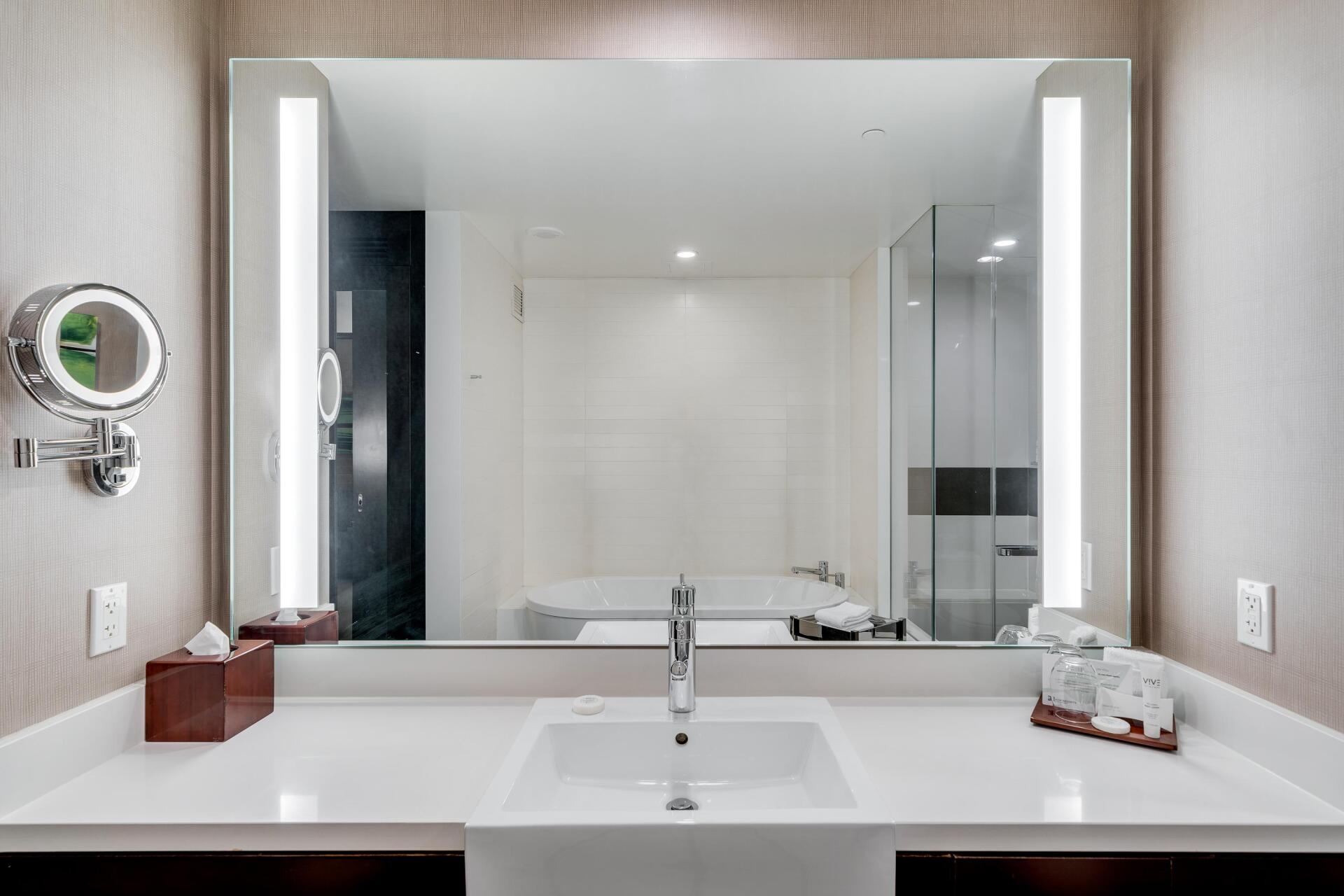 Modern bathroom vanity with large mirror, white sink, and neutral gray walls