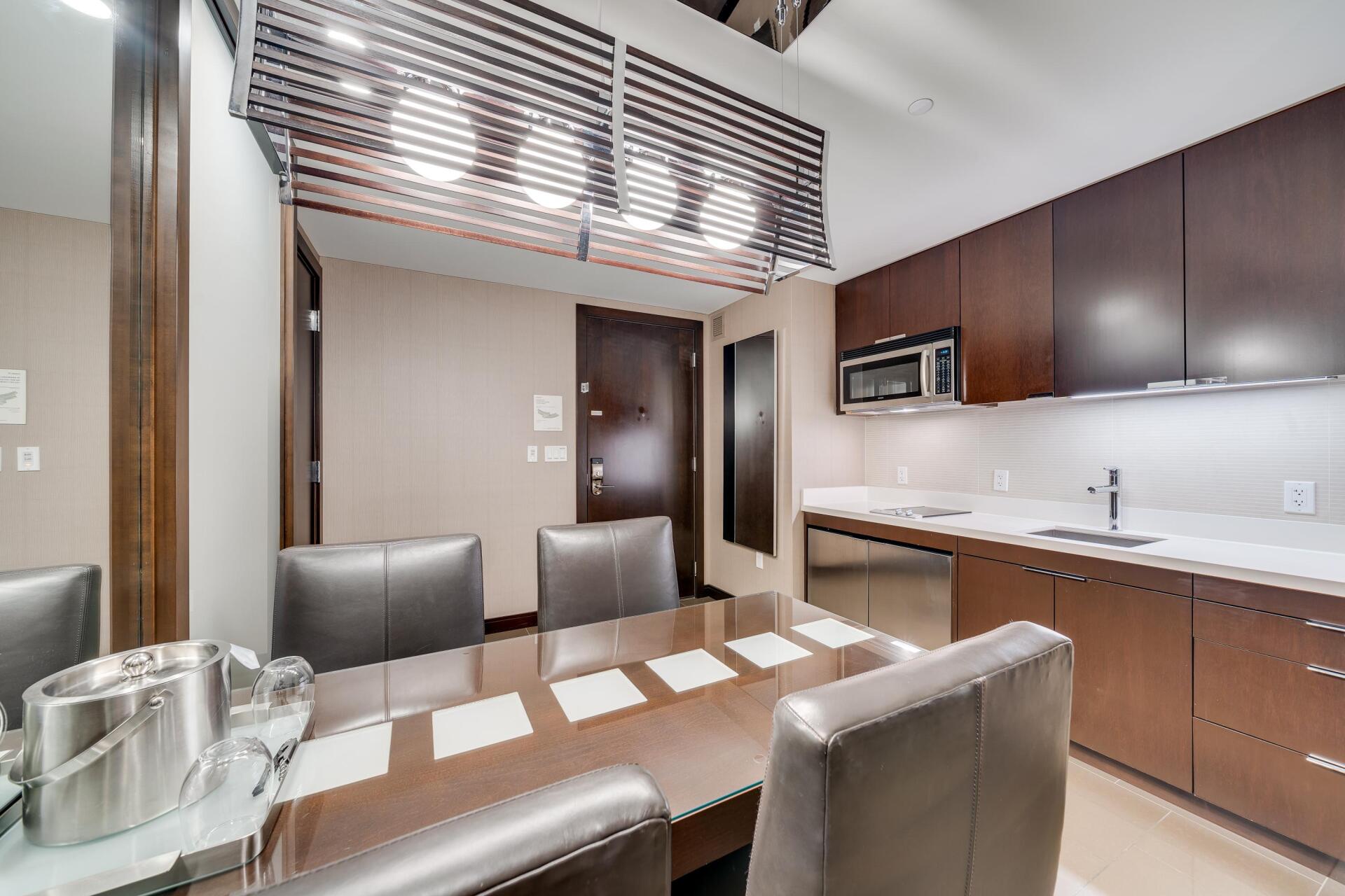 Modern kitchen and dining area with dark wood cabinets, stainless appliances, and a table set for a meal
