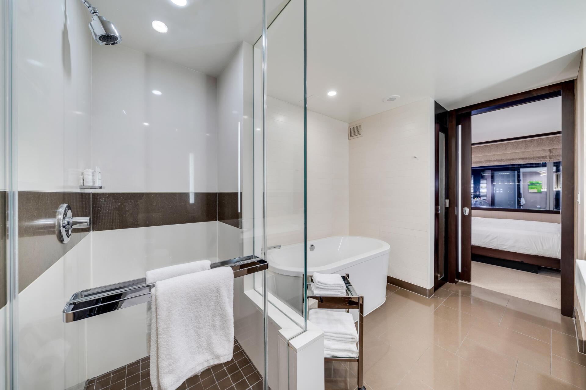 Modern bathroom with glass shower, freestanding tub, and large window view