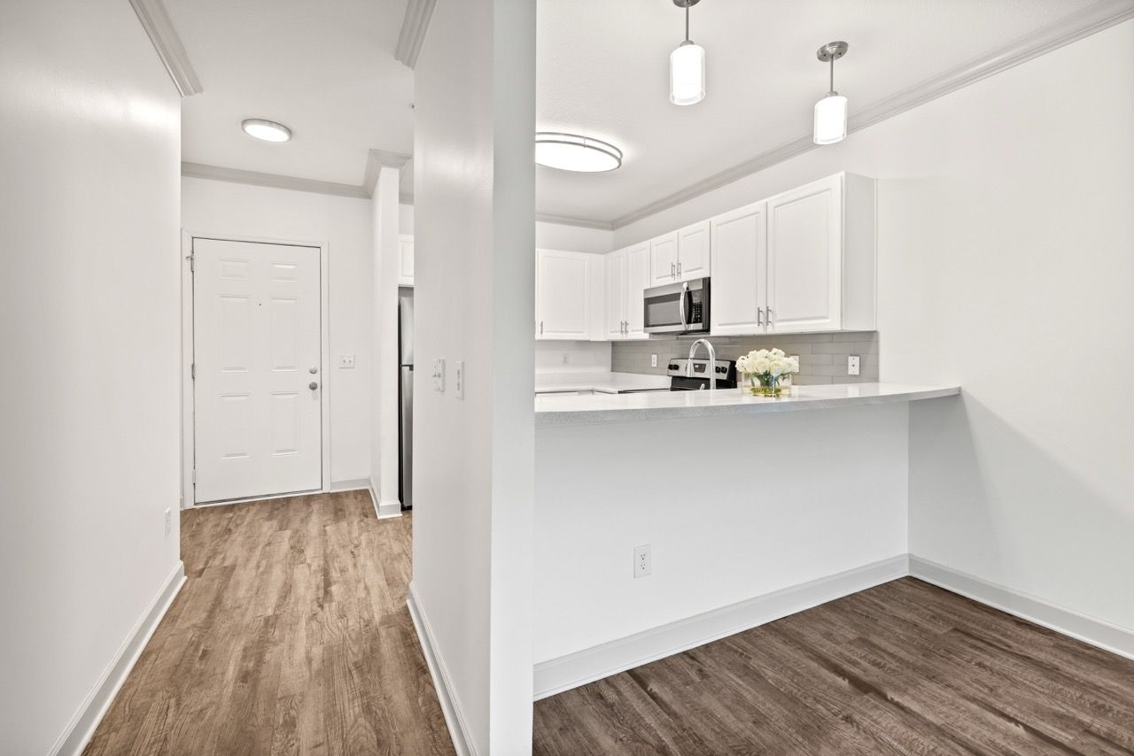 Bright open kitchen with white cabinets, stainless appliances, and a breakfast bar.