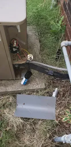 Bowling Heating & Conditioning LLC Spray Foam- A broken air conditioner is sitting on the ground next to a brick wall.