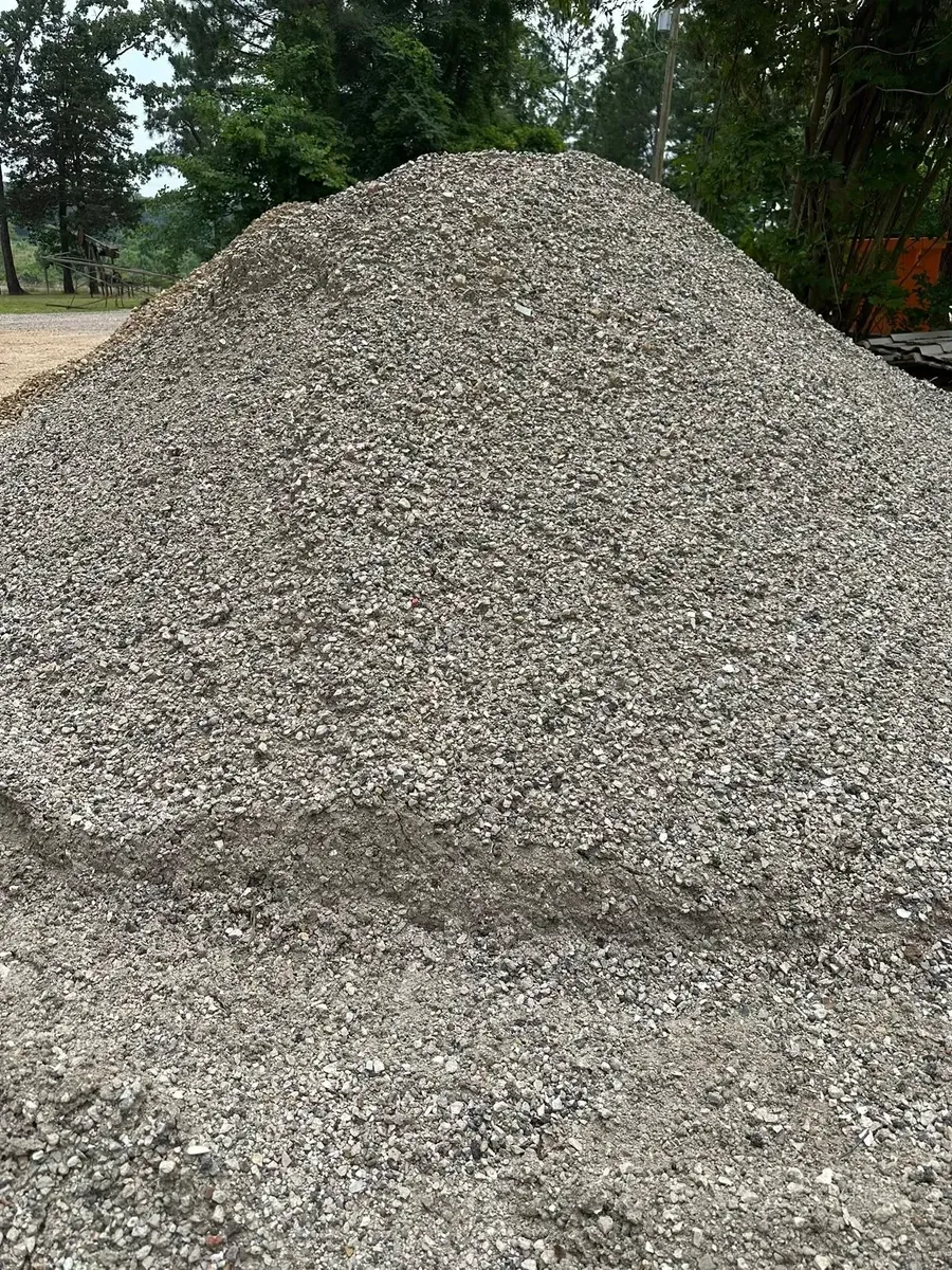 Large pile of gray gravel outdoors with trees in the background