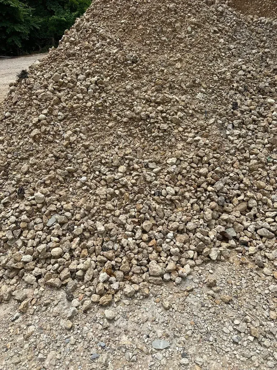 Large pile of small tan gravel or crushed stones outdoors on a dirt surface.