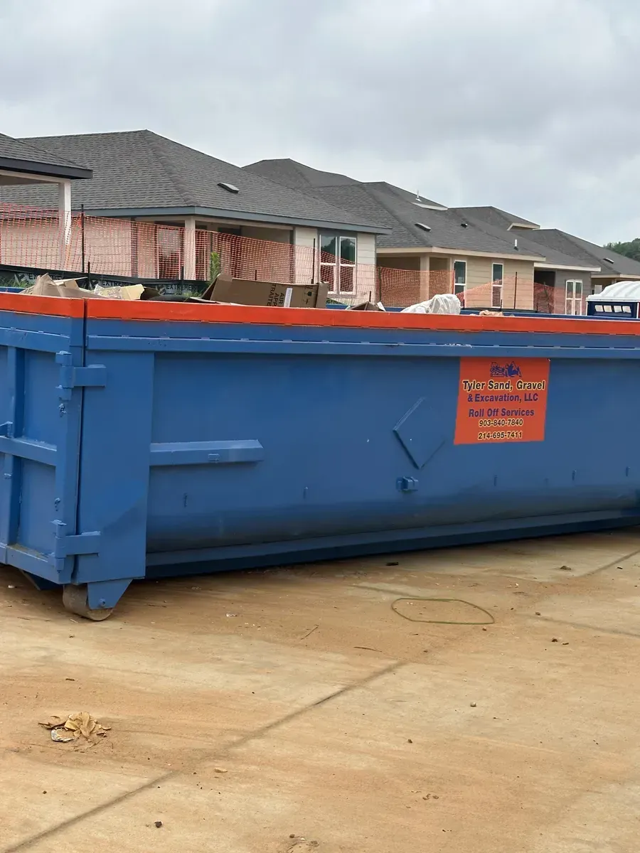 Large blue construction dumpster on a driveway in a suburban neighborhood