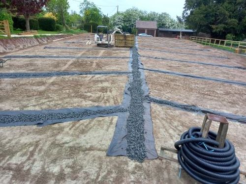 A hose is laying on the ground next to a pile of gravel.