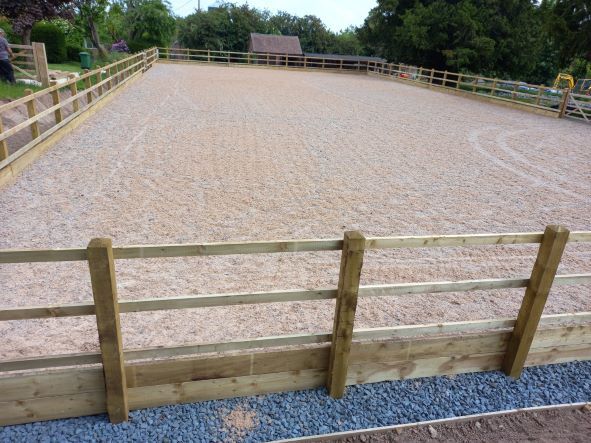 A wooden fence surrounds a large dirt field