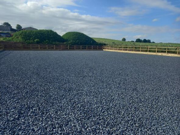 A large gravel area with a wooden fence in the background