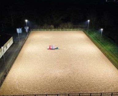 An aerial view of a horse arena at night.